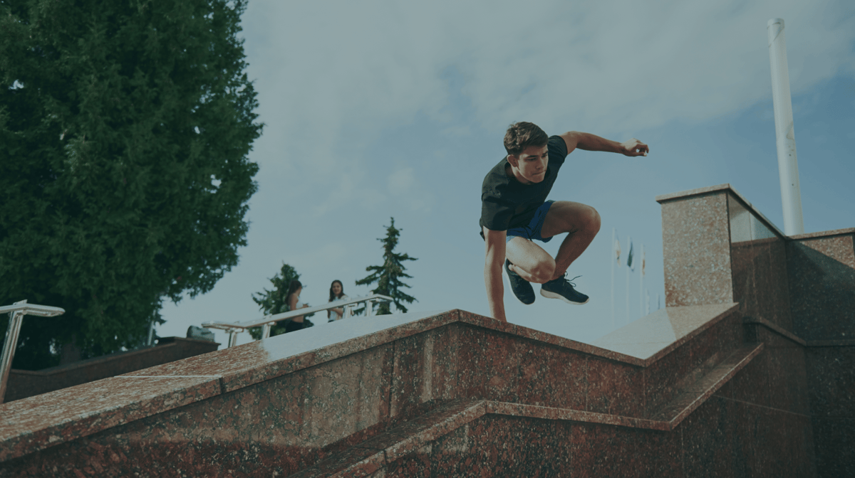 A young man jumping over a stair wall while doing parkour